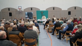 Menschen in der Sporthalle bei christlichen Gottesdienst, vorne Pater am Altar Gabenbereitung.