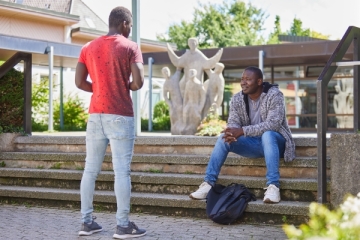 Badu Ba unterhält sich mit Freund am Eingang des Salesianums