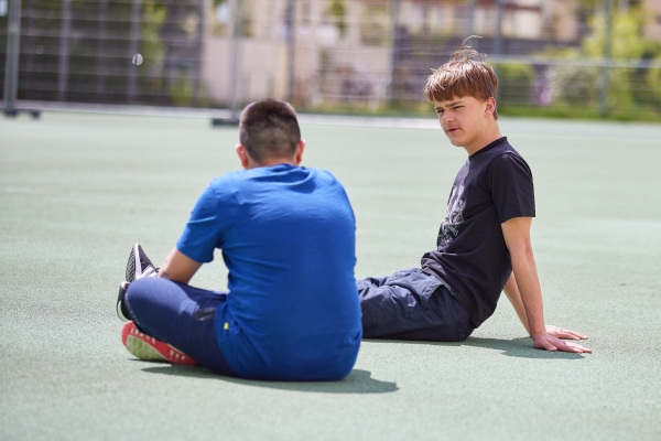 Zwei Jungen aus dem Oratorium sitzen auf dem Fußballplatz