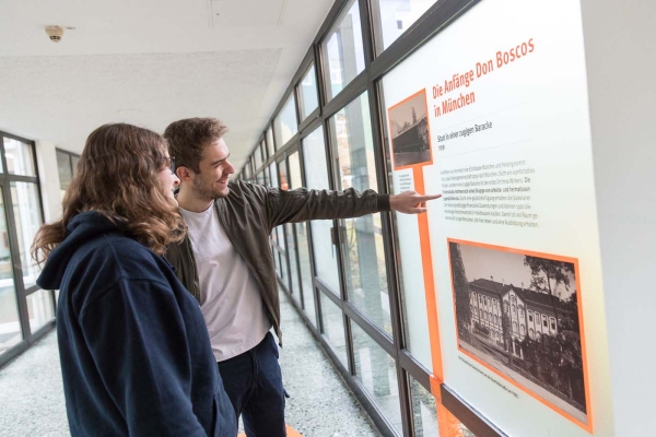 Junge Menschen schauen sich die Ausstellung zum Jubiläum der Einrichtung an