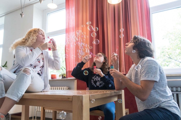 Junge Menschen machen in der Lounge Seifenblasen