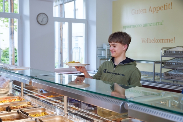 Jugendlicher an der Theke zur Essenausgabe