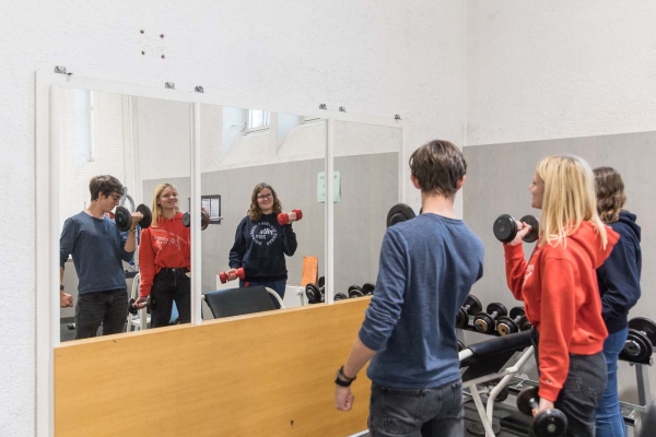 Junge Menschen heben Hanteln im Fitnessraum des Salesianums