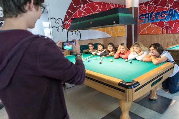 Junger Mann macht Foto von einer Gruppe junger Menschen am Billardtisch