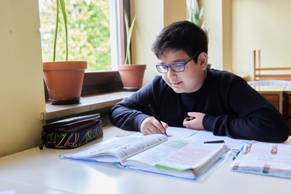 Ein Junge vor seinen Schulbüchern im Oratorium