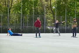 Junge Menschen spielen auf dem Platz vor dem Oratorium Fußball.