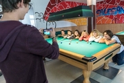 Junger Mann macht Foto von einer Gruppe junger Menschen am Billardtisch