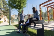 Junge Menschen sitzen auf der Bank vor dem Sportplatz und unterhalten sich
