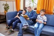 Erzieherin liest mit zwei Jungen ein Buch in der Couchecke