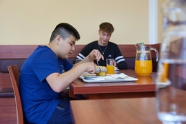 Kind und Erzieher aus dem Oratorium beim Mittagessen im Speisesaal